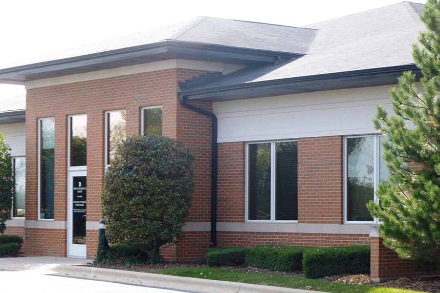 About Our Agency - Angled View of Merit Insurance Group Office Front Displaying Brick and Greenery on a Sunny Day