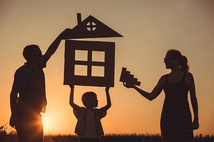 Personal Insurance - Silhouette of Family Constructing a House in a Field at Sunset with an Orange Sky